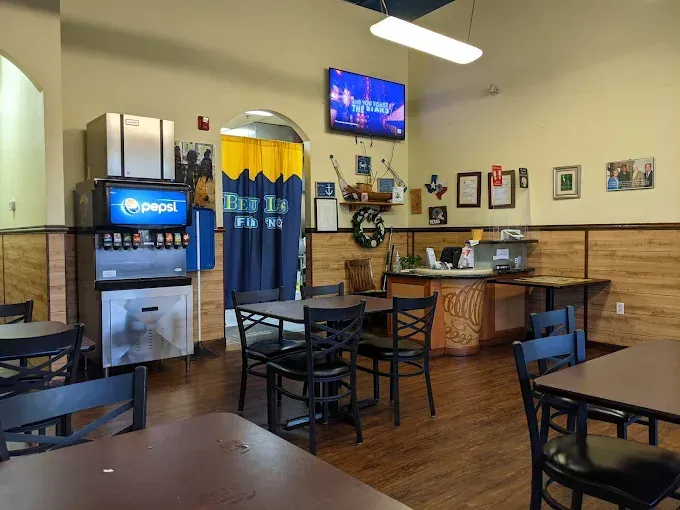 Empty restaurant dining area with tables, chairs, a soda fountain, and a TV on the wall