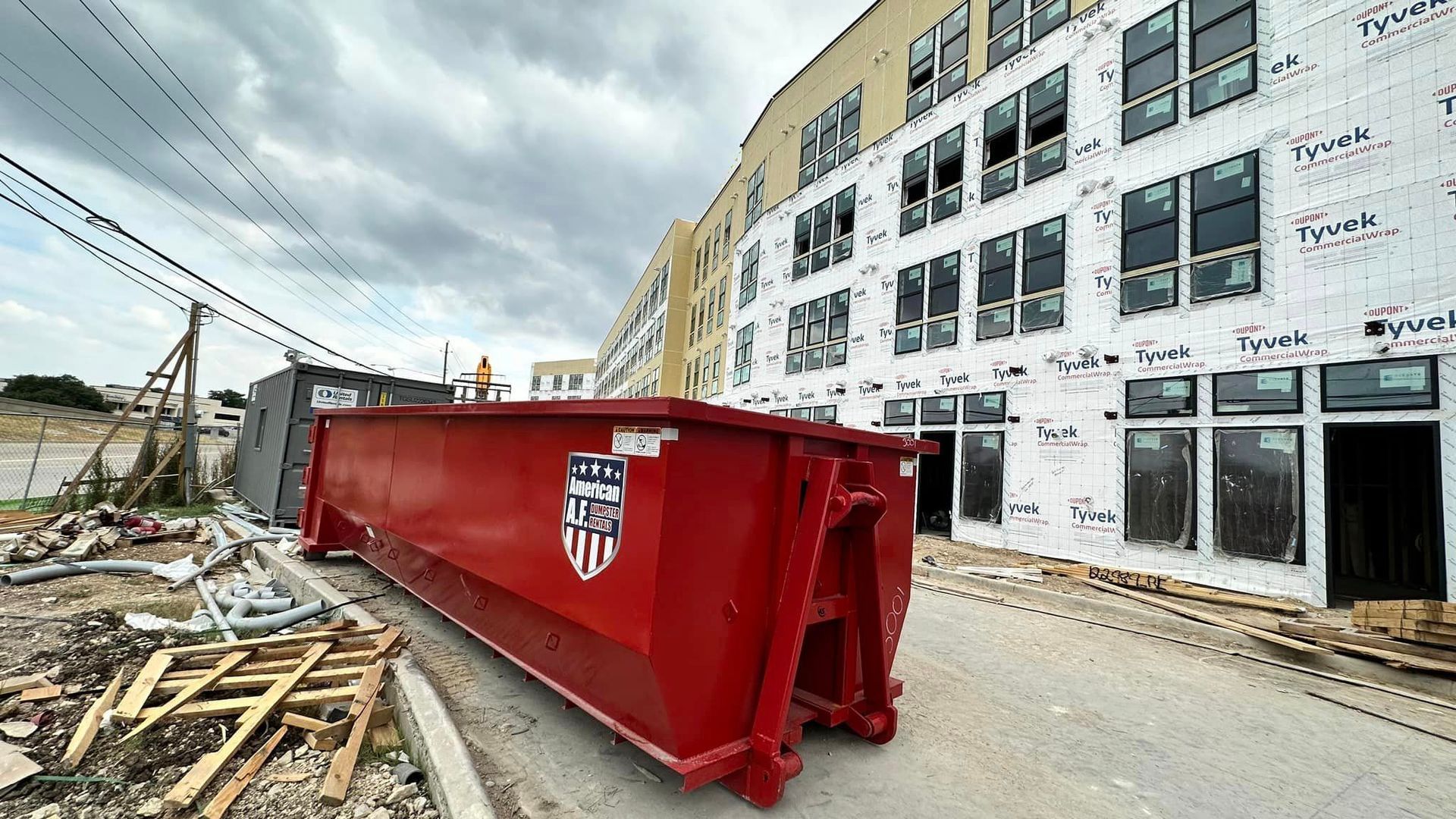 a large red 30 yard dumpster is parked in front of a building under construction .