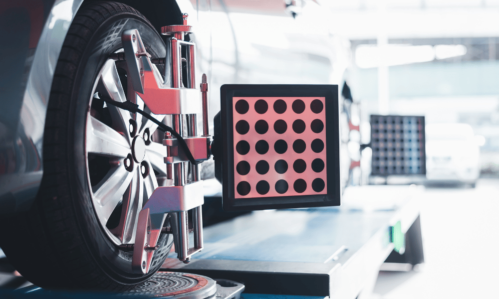 Wheel alignment machine attached to car tire in auto repair shop