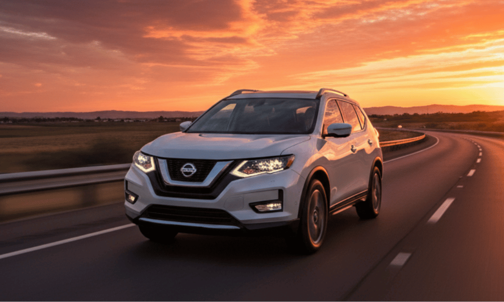 White Nissan SUV driving on highway at sunset
