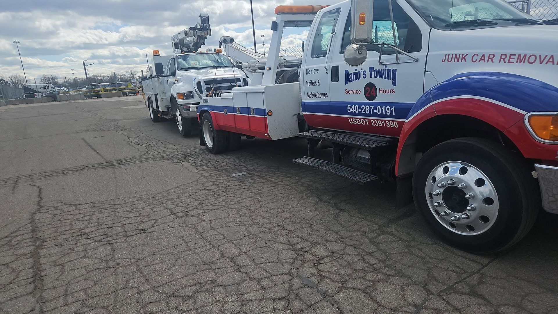Tow truck convoy parked on a cracked lot, with white and red service trucks lined up.