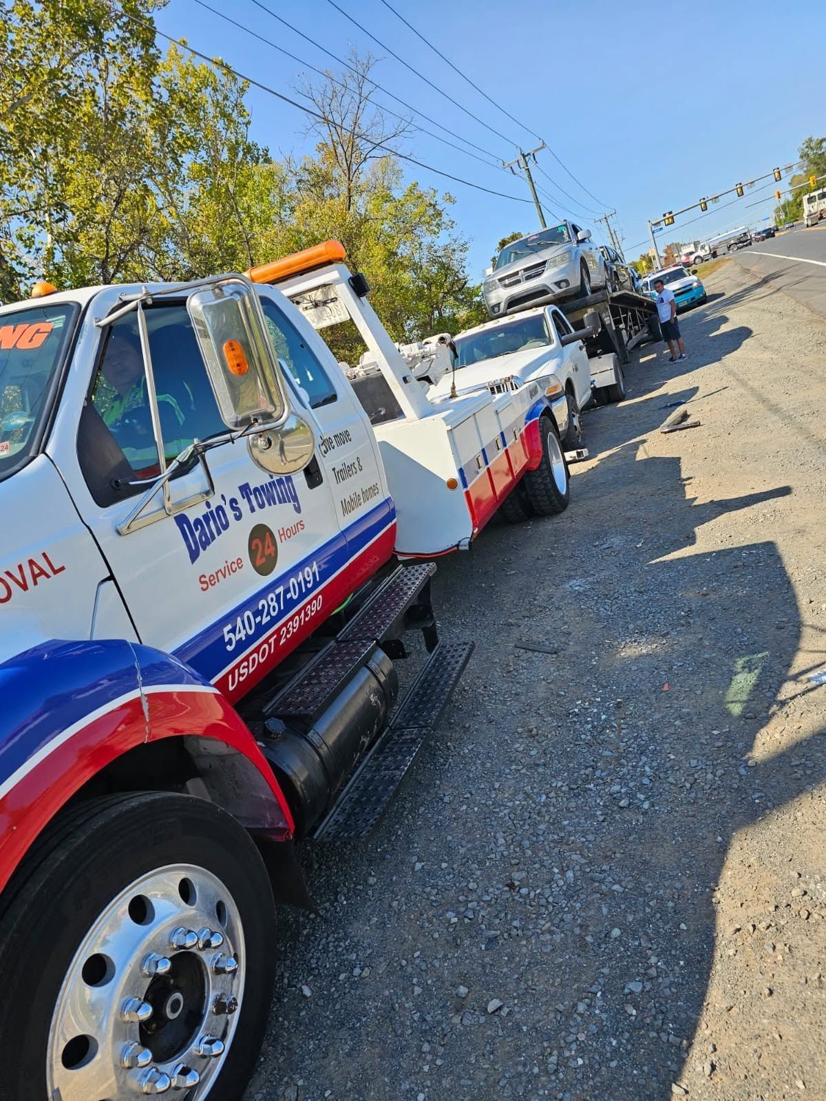 Tow truck convoy on a sunny roadside, with red, white, and blue service trucks lined up behind one another