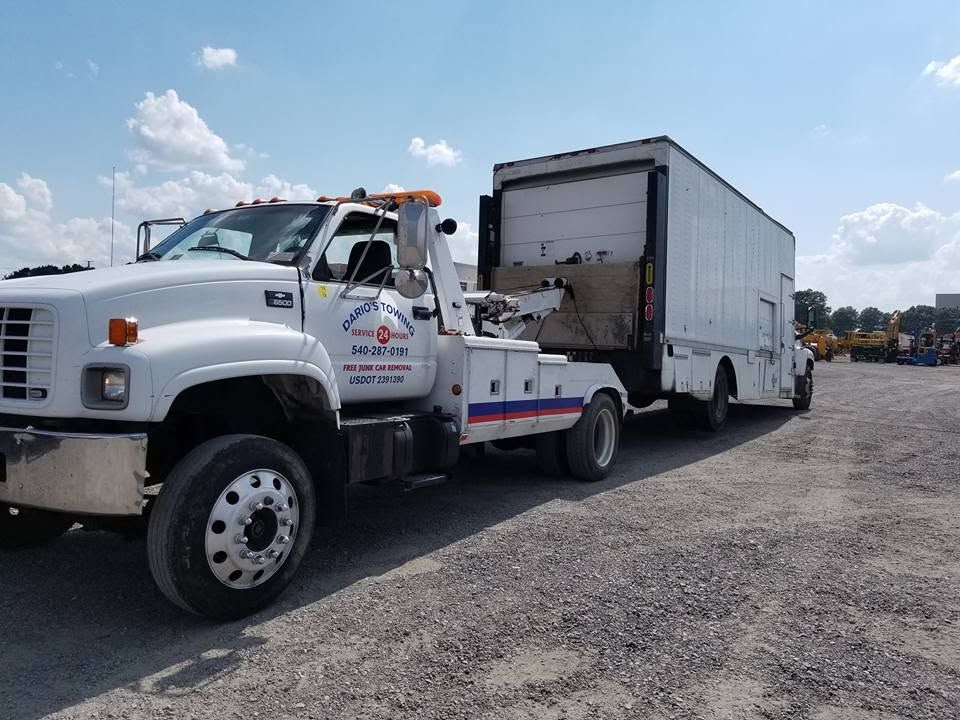 White dump truck hauling a gray trailer on a gravel lot under a partly cloudy sky
