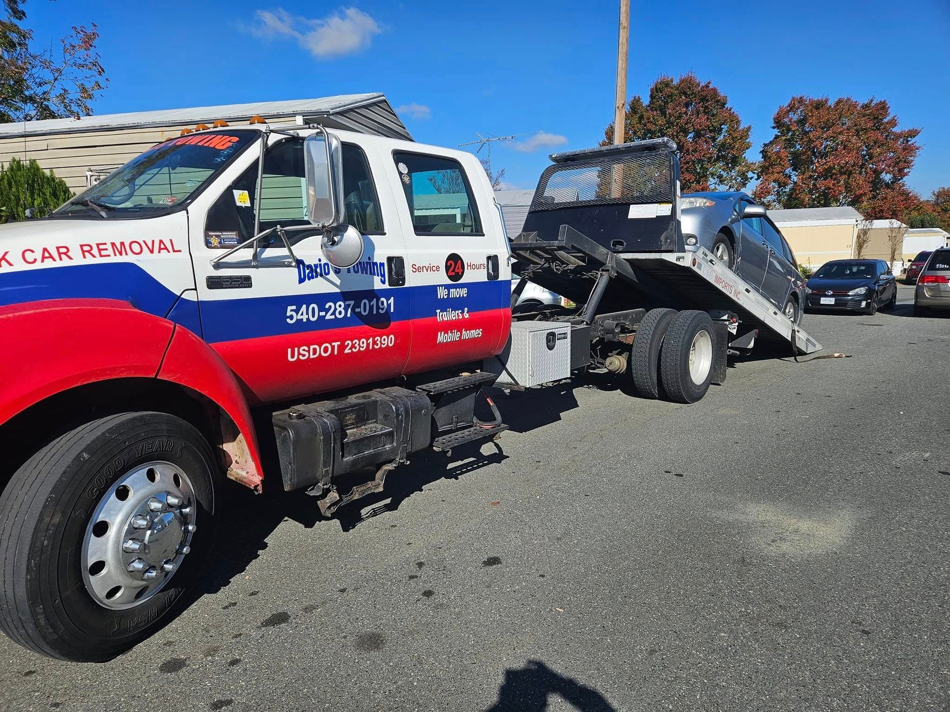Red and white tow truck hauling a car on a trailer in a parking lot