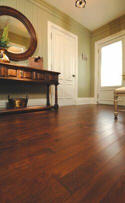A hallway with hardwood floors and a mirror on the wall.