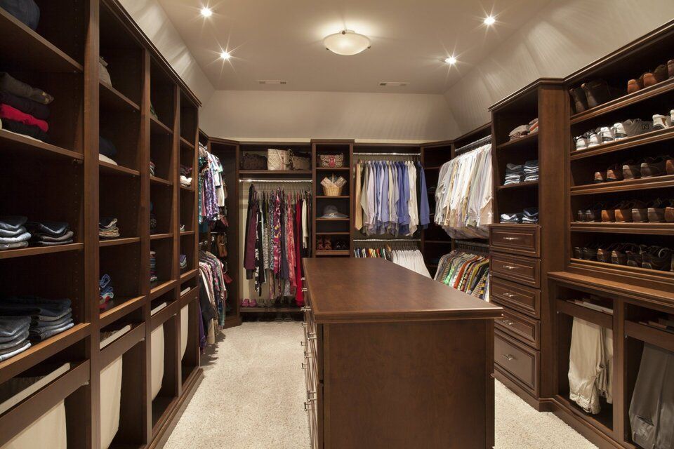 A large walk in closet filled with lots of clothes and shoes.