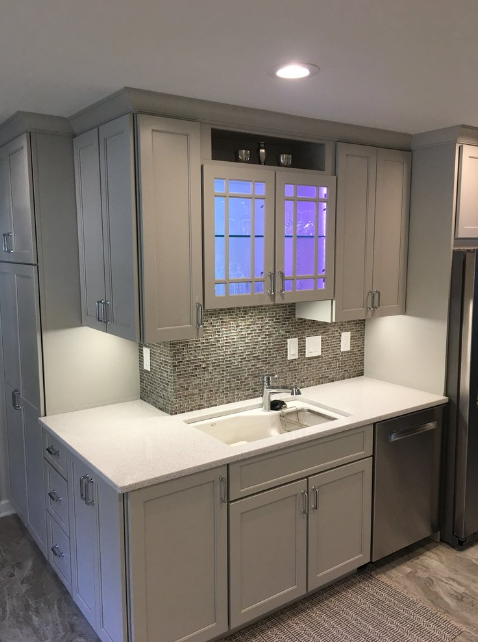 A kitchen with white cabinets , stainless steel appliances , a sink and a refrigerator.