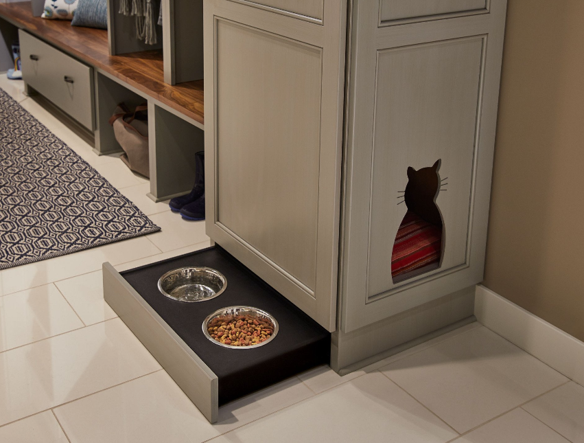 A cat house with two bowls of food underneath it