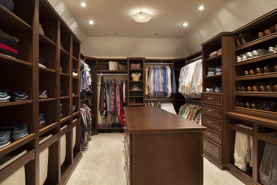 A large walk in closet filled with lots of clothes and shoes.