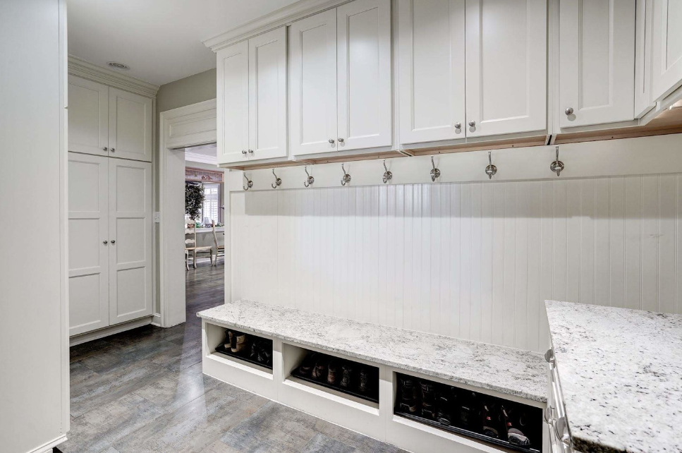 A mud room with white cabinets and a bench.