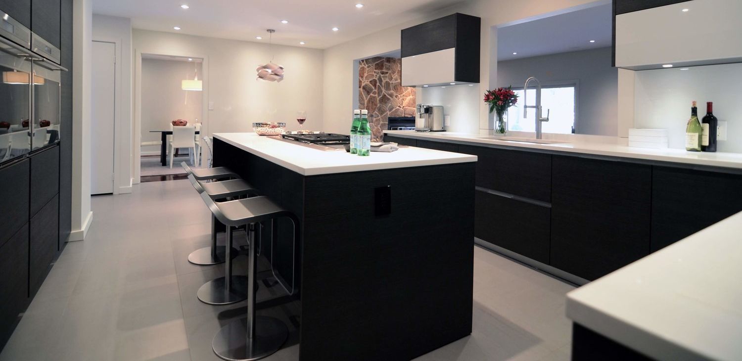 A kitchen with black cabinets and white counter tops and a large island in the middle.
