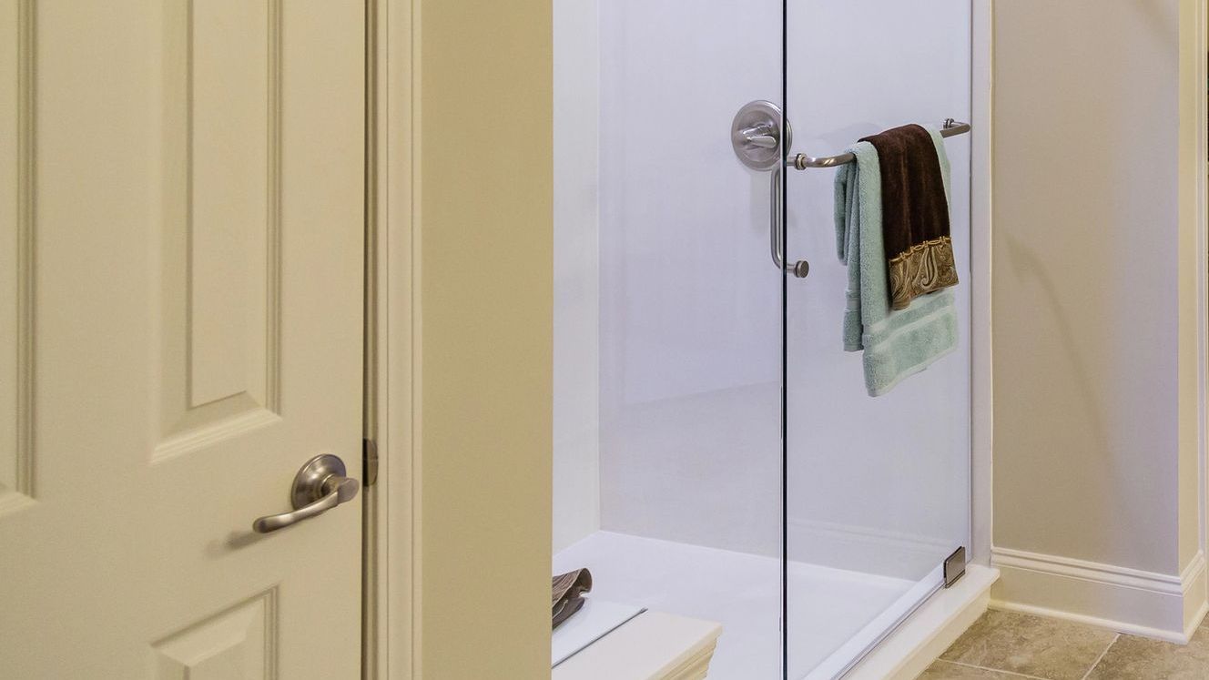A bathroom with a walk in shower with a glass door.
