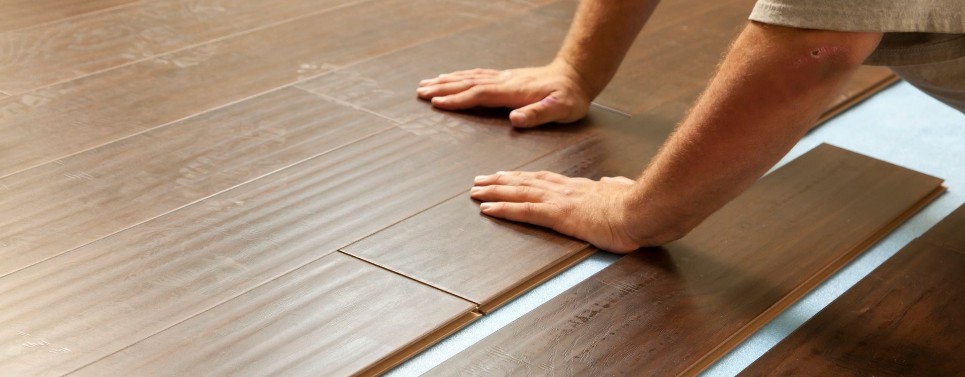 A person is installing a wooden floor in a room.