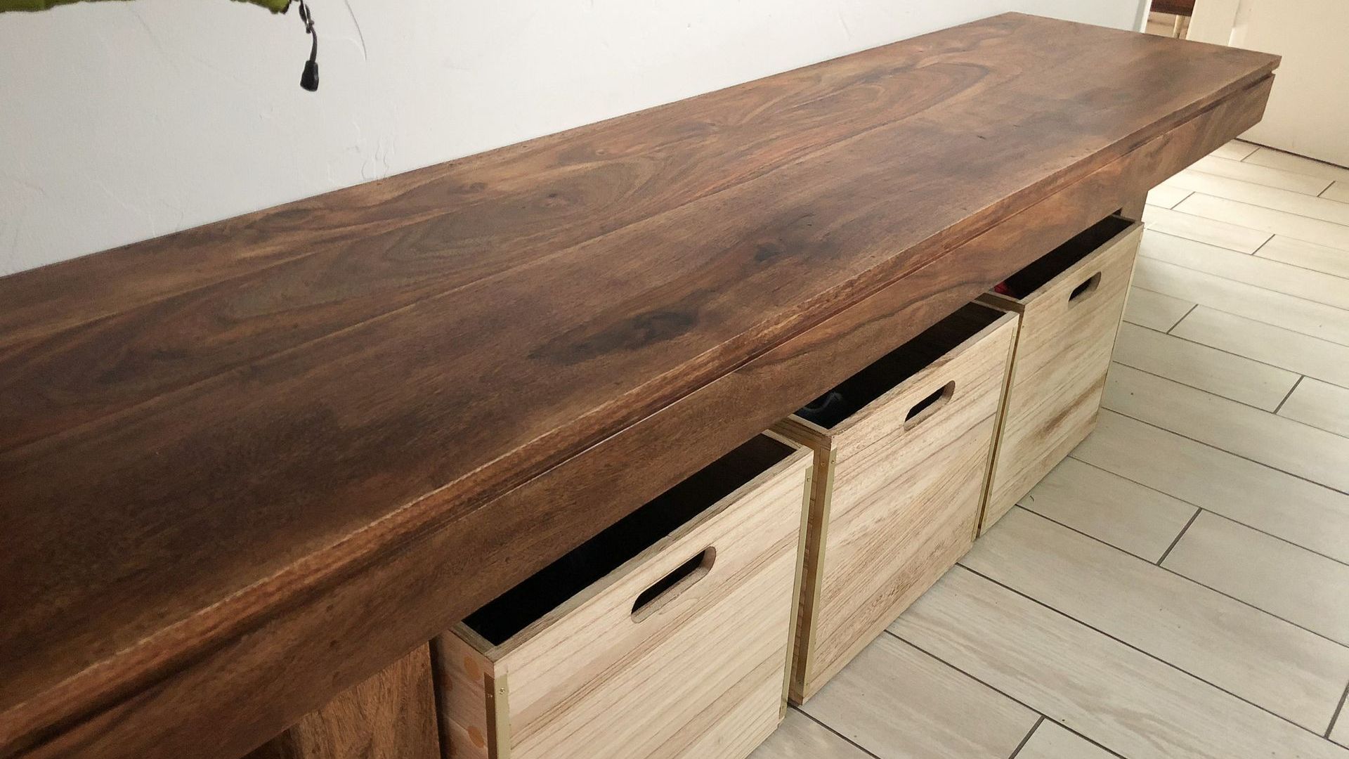 A wooden bench with drawers underneath it in a room.