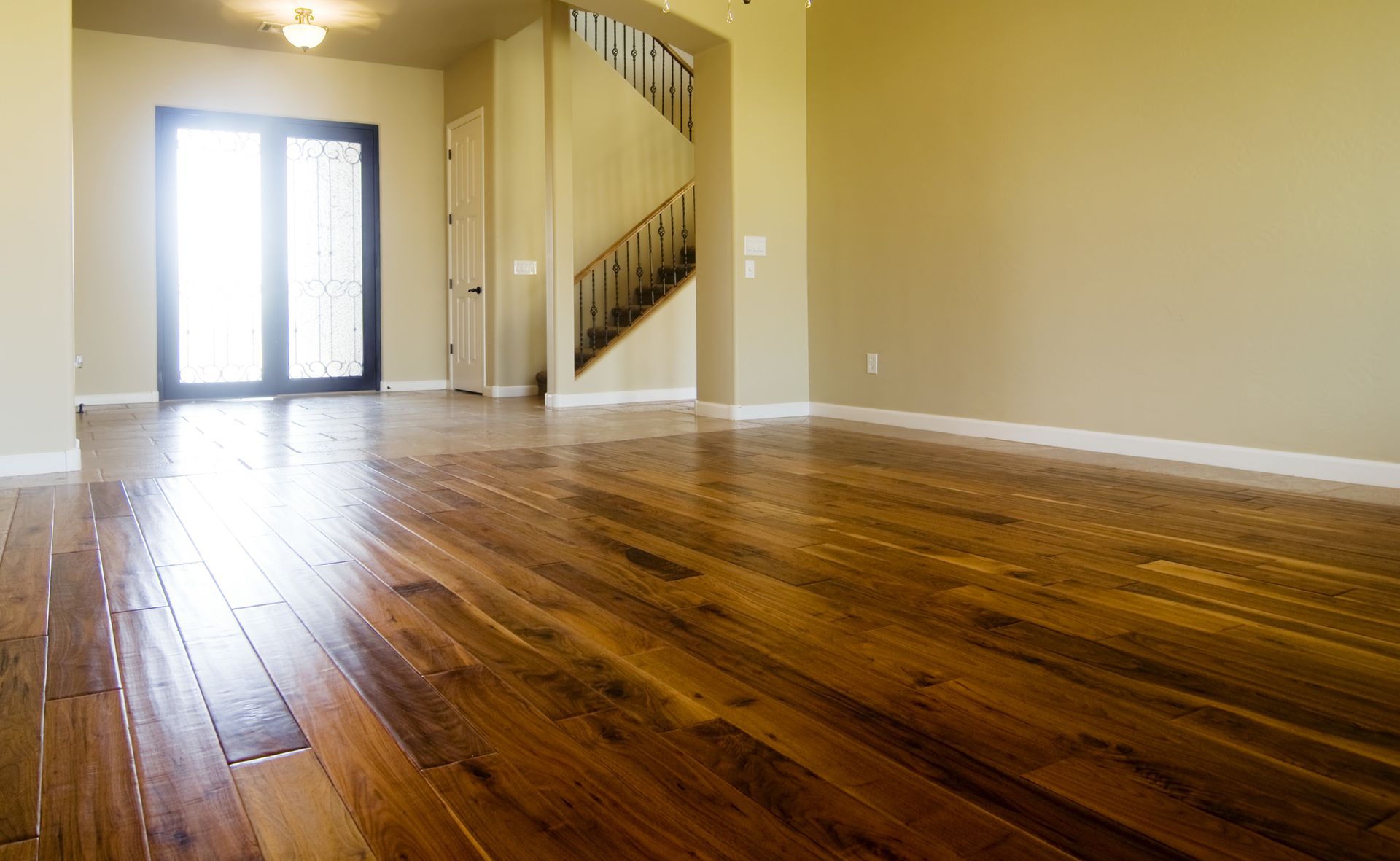 An empty living room with hardwood floors and a staircase.