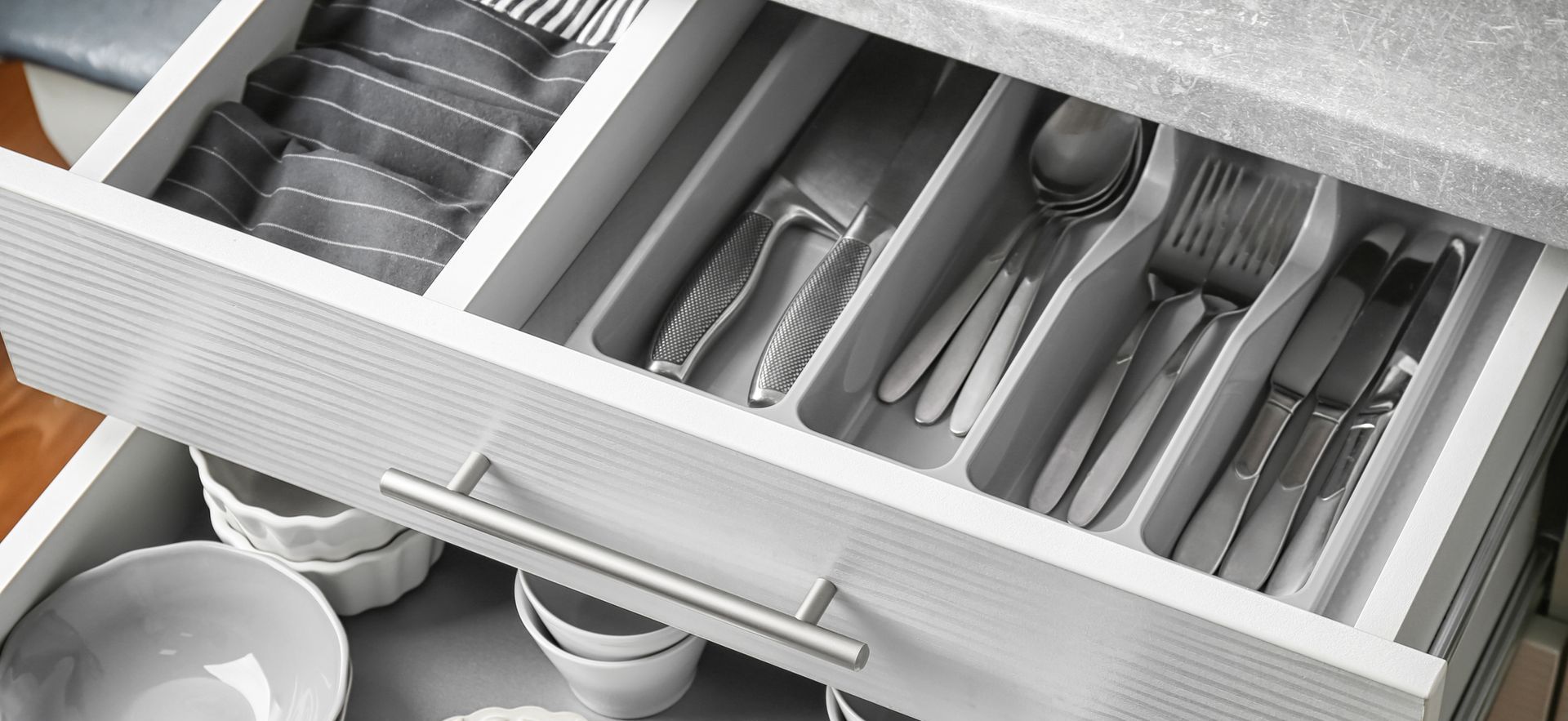 A kitchen drawer filled with utensils and bowls.
