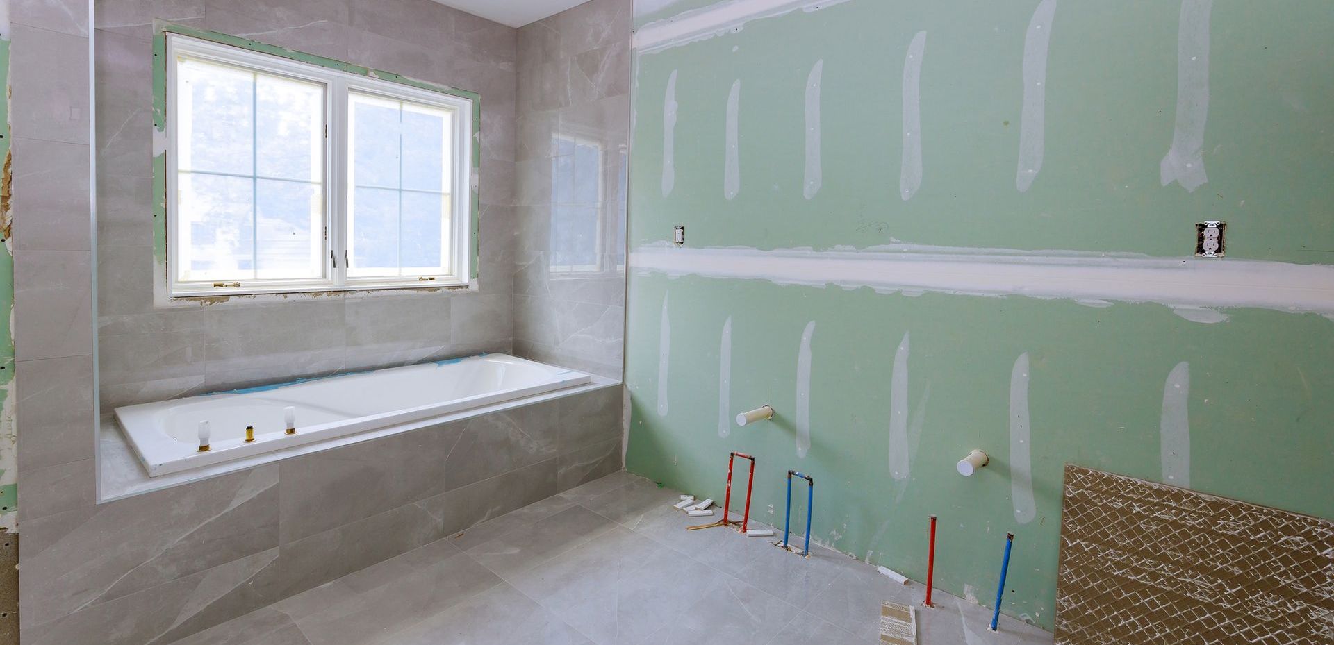 A bathroom remodel under construction with a bathtub and a window.