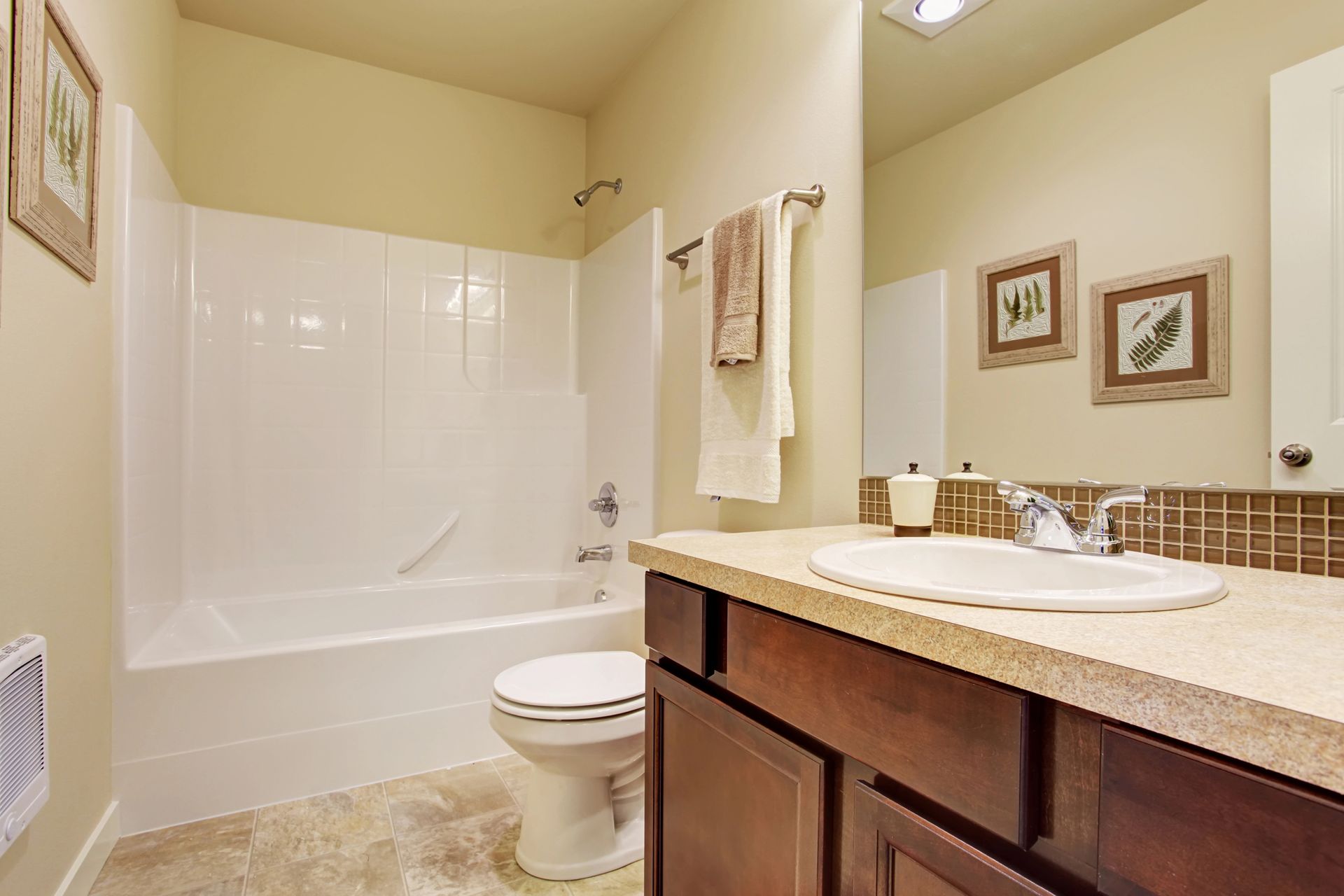 A bathroom with a toilet , sink , bathtub and mirror.