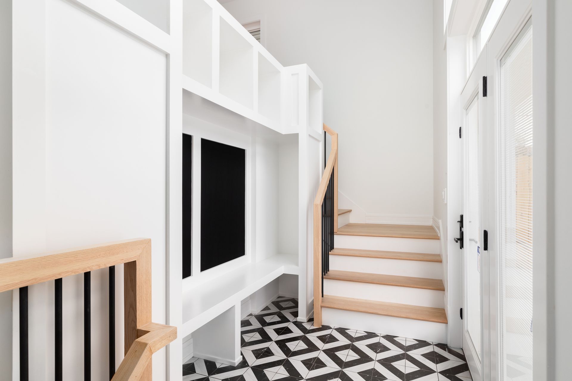 A hallway with stairs and a tv on the wall.