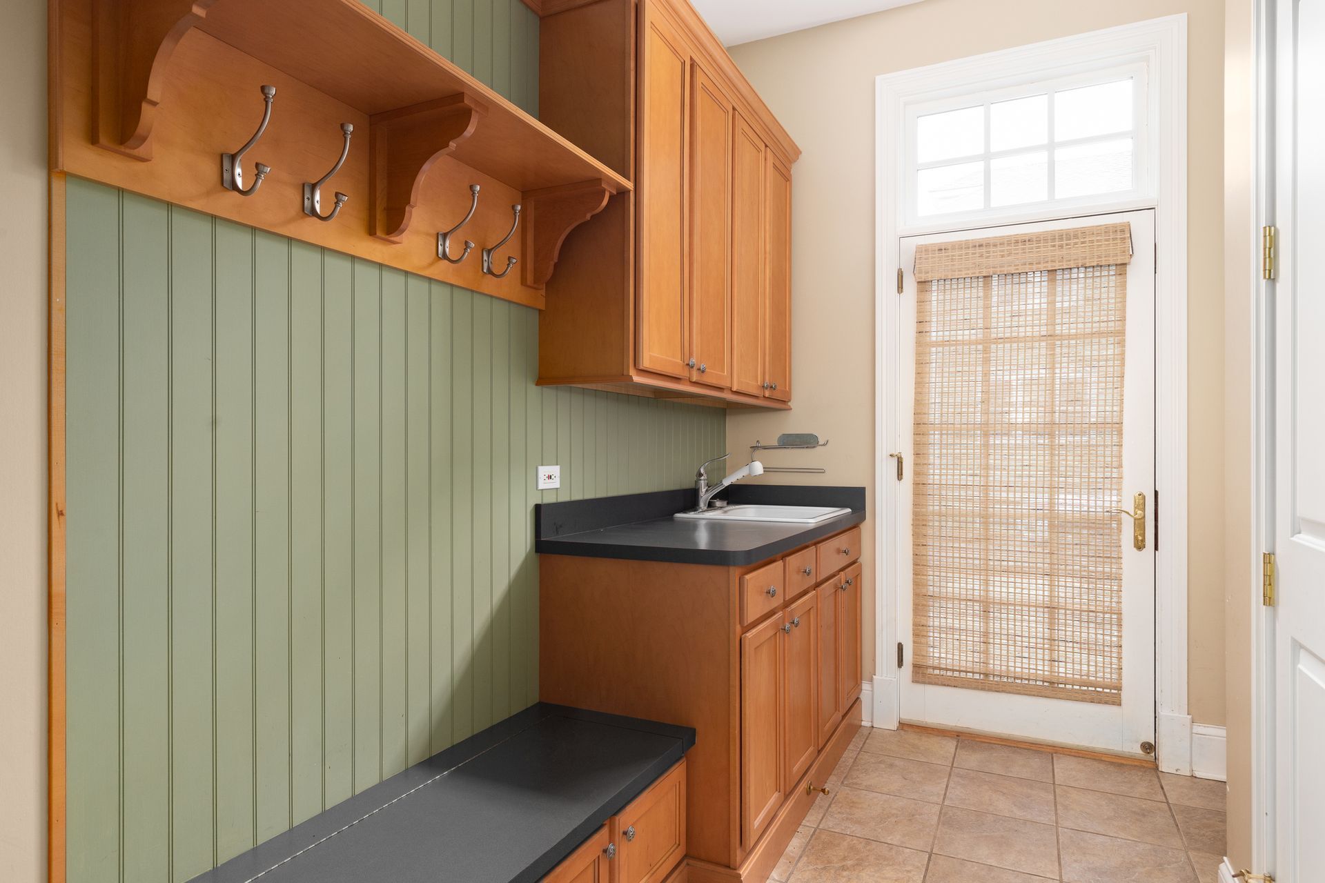 A laundry room with wooden cabinets and a sink.