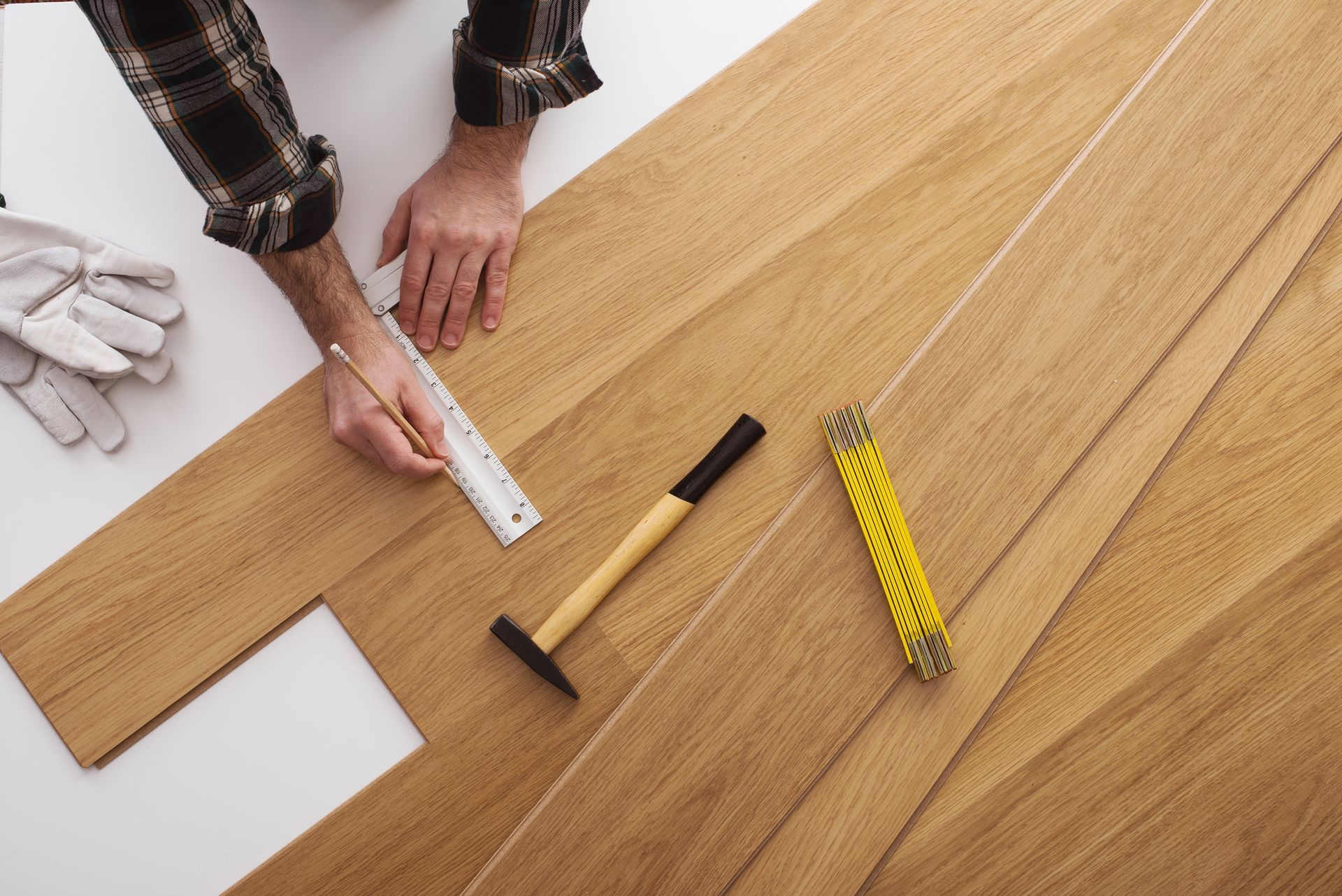 A person is measuring a piece of wood with a ruler and hammer.