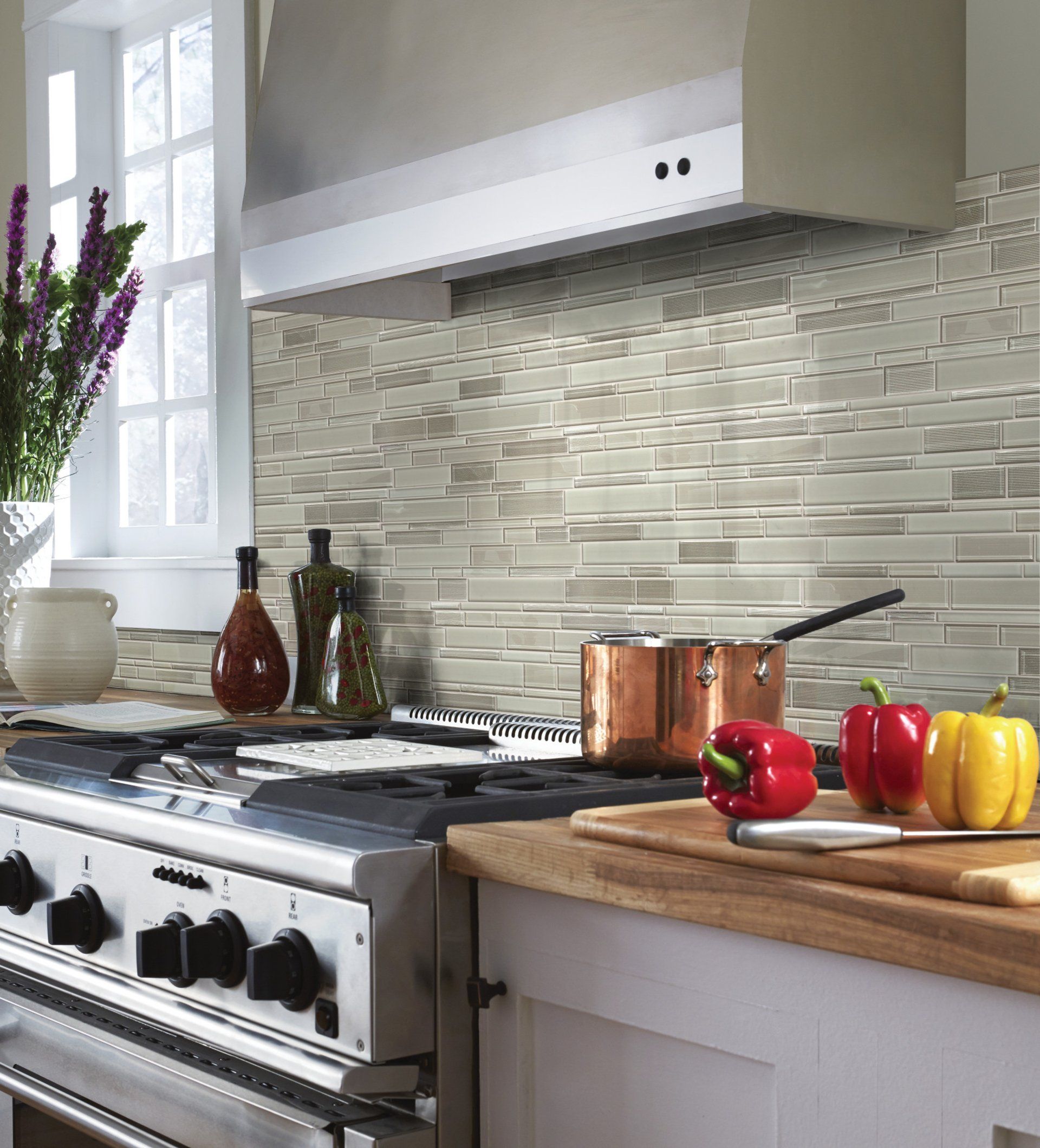 A kitchen with a stove and a cutting board with peppers on it.