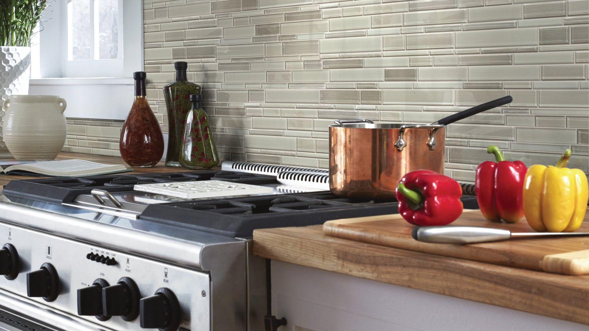 A kitchen with a stove , pots and peppers on the counter.