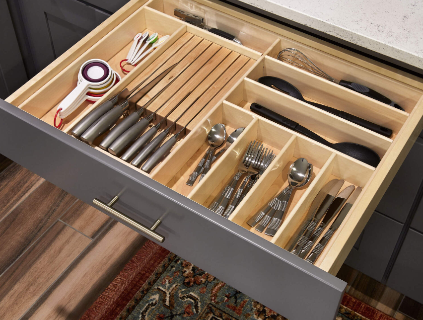 A kitchen drawer filled with knives , forks , spoons and measuring cups.