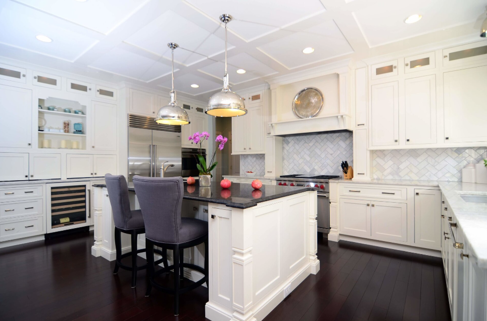 A kitchen with white cabinets , stainless steel appliances , and a large island.