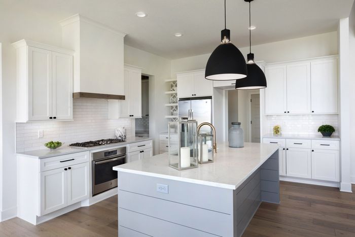 A kitchen with white cabinets , stainless steel appliances , and a large island.