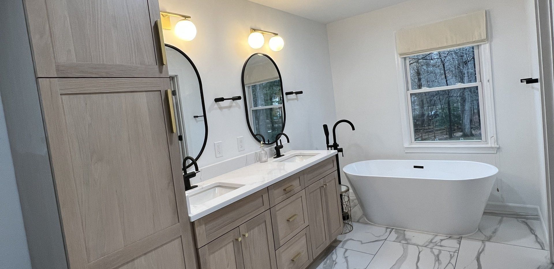 A bathroom with two sinks , a tub , two mirrors and a window.