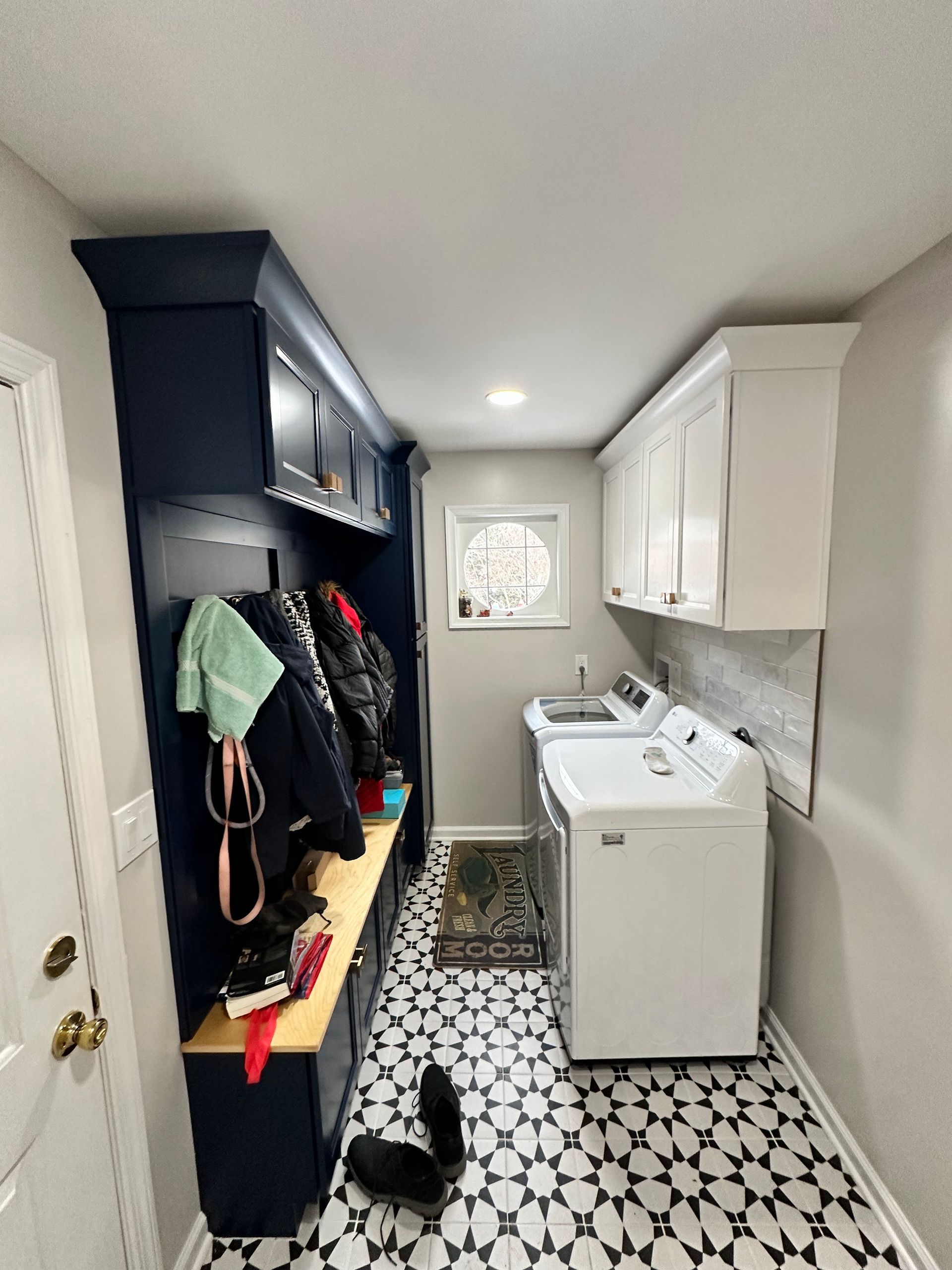 A laundry room with a washer and dryer and a bench.