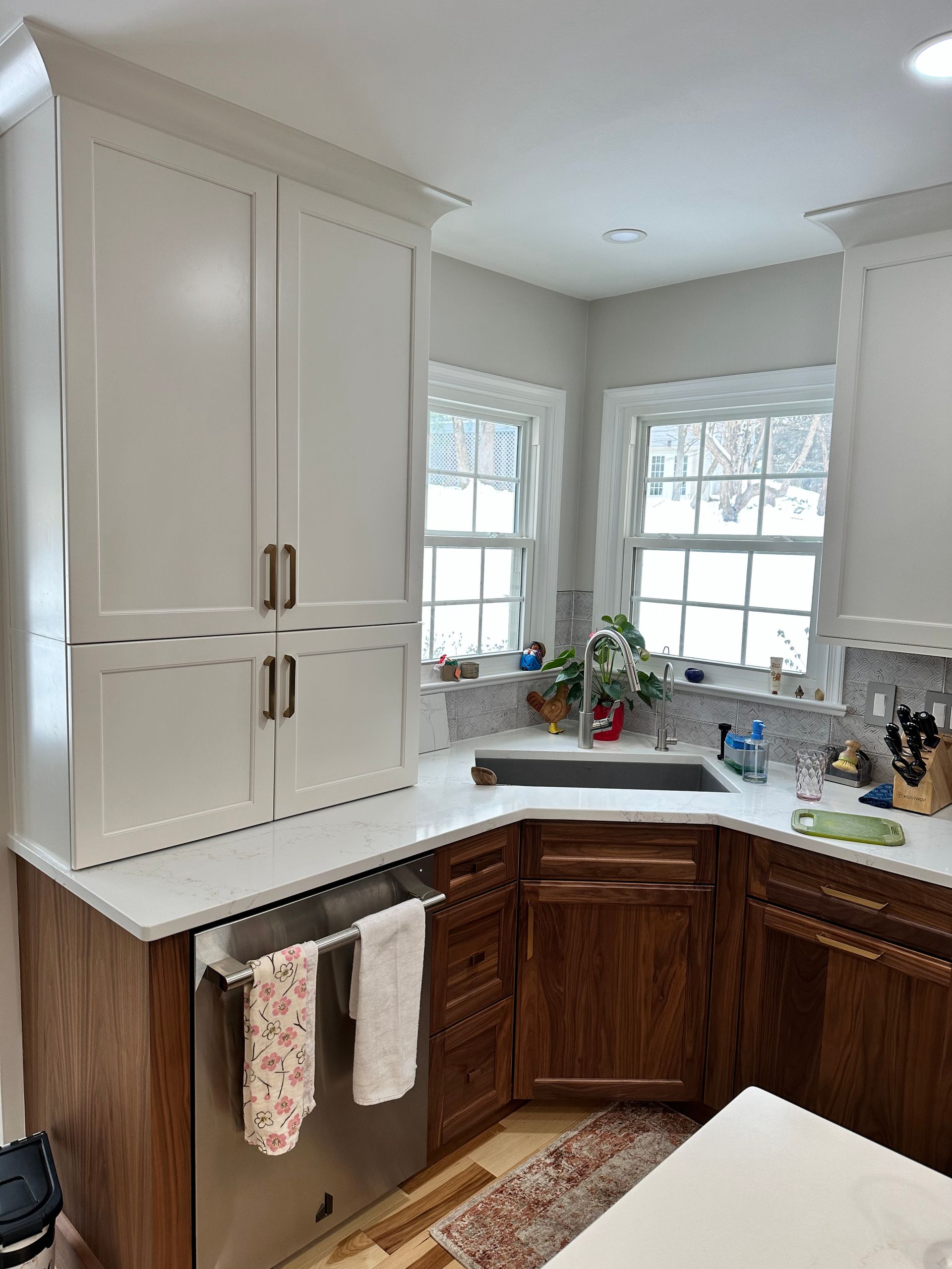 A kitchen with wooden cabinets , stainless steel appliances , a sink , and a window.