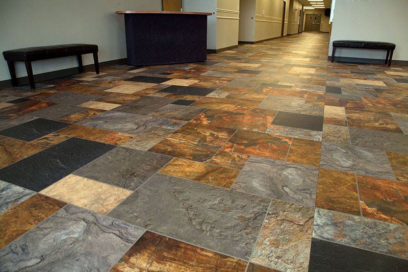 A hallway with a tiled floor and a desk in the background.
