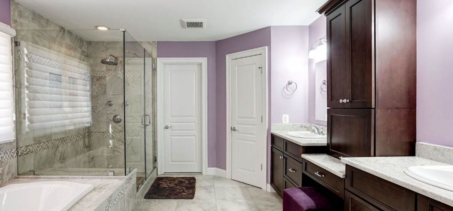 It is a bathroom with purple walls and a walk in shower.