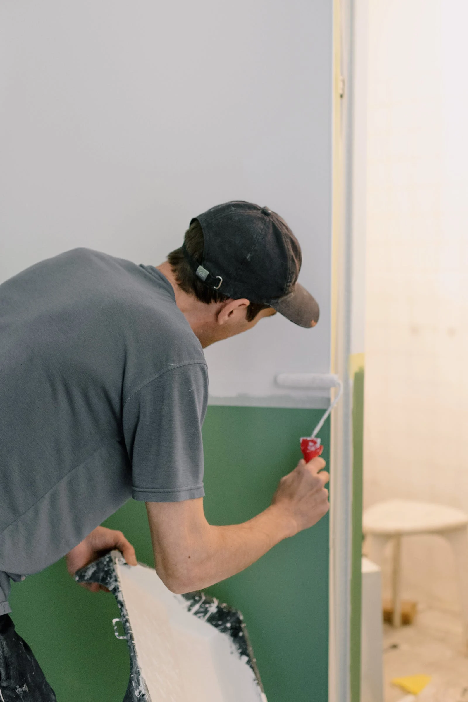 A man is painting a wall with a paint roller.