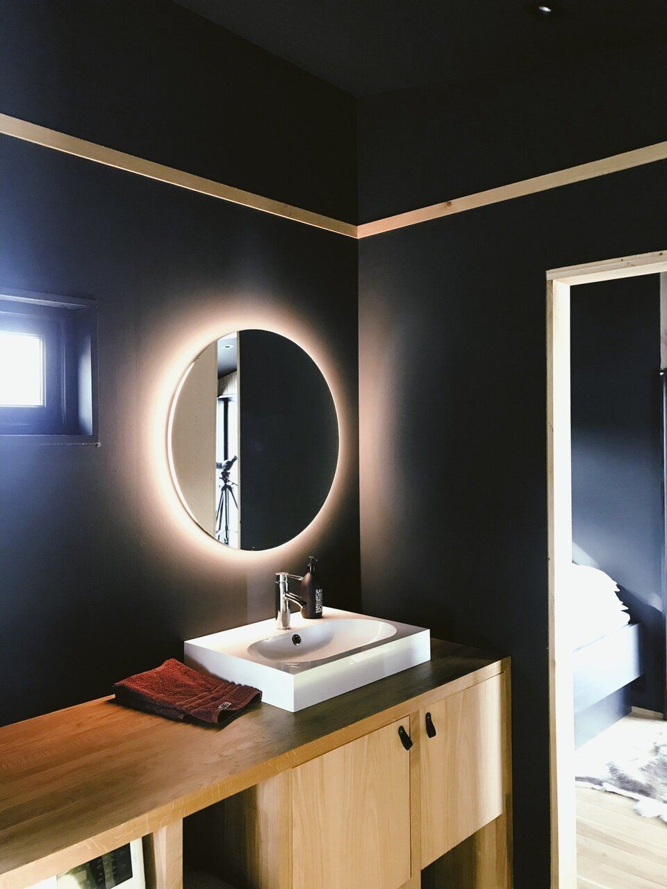 A bathroom with a sink and a round mirror