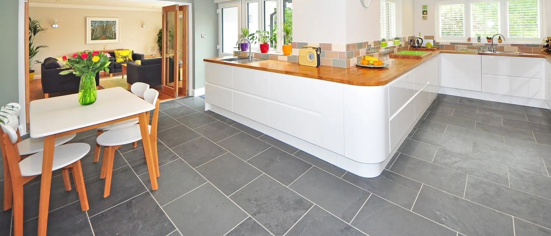 A kitchen with a table and chairs and a black tile floor.