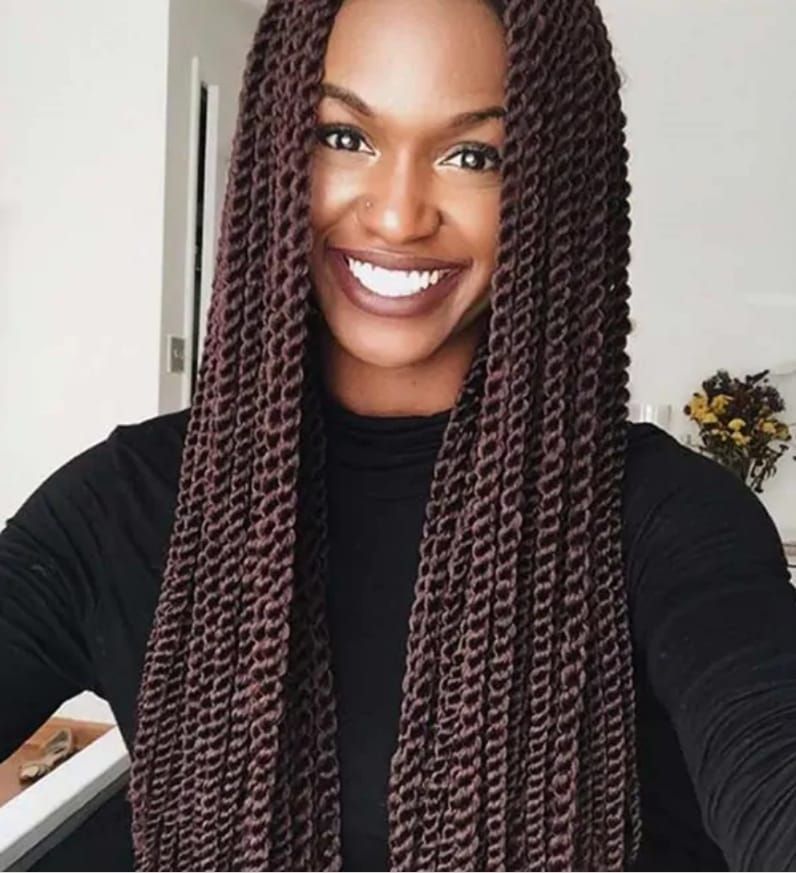 A woman with braids is smiling and wearing a black shirt