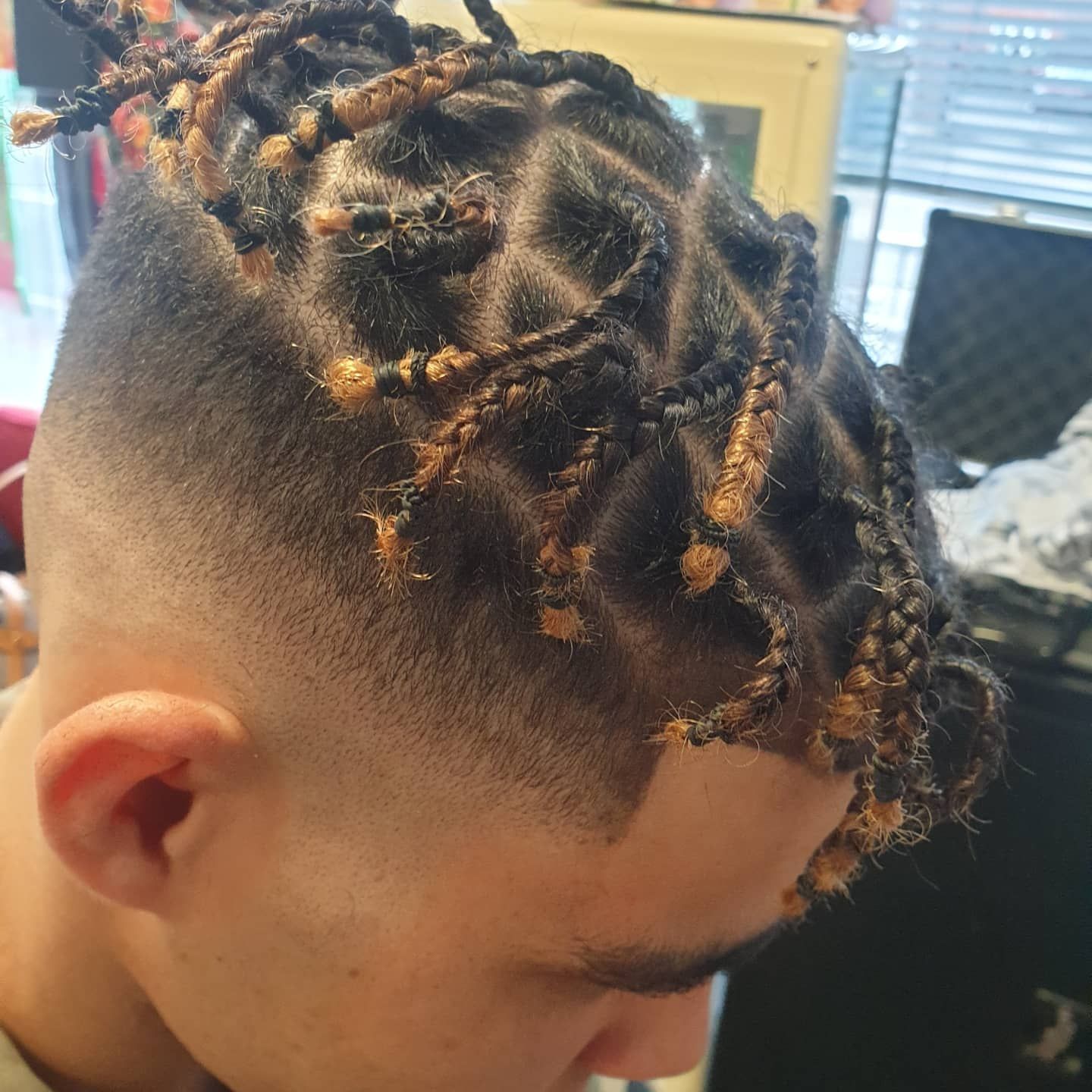 A man with braids in his hair has a shaved head