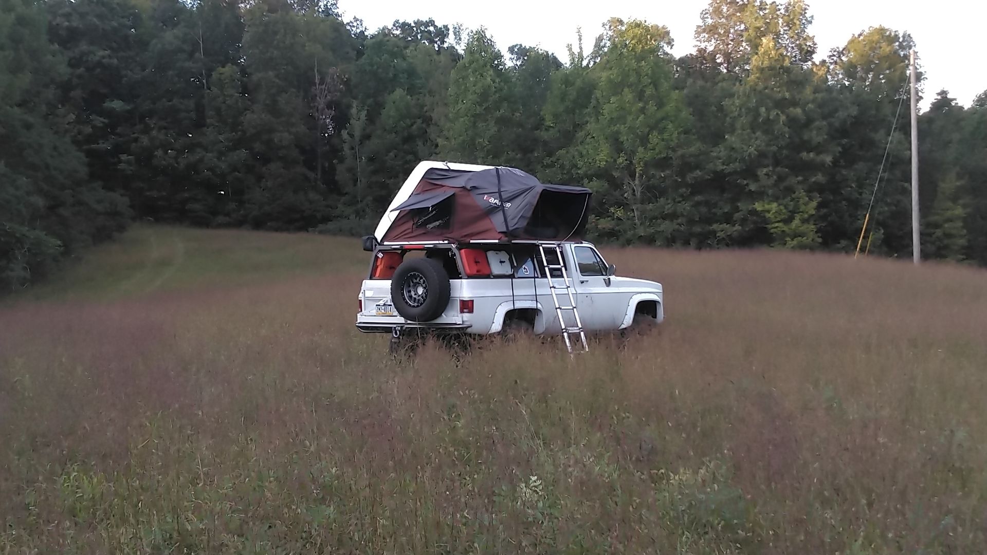 Overlanding truck with a bed rack supporting a roof top tent