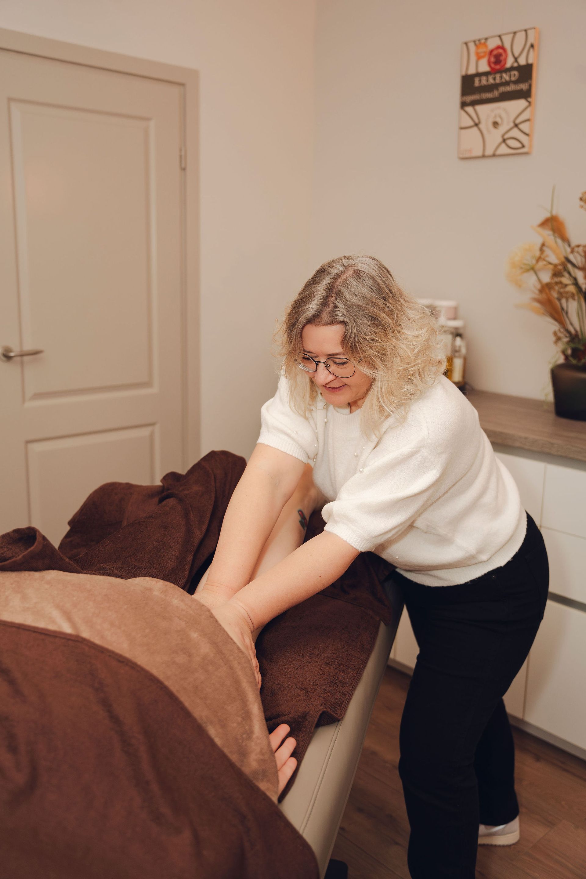 Een vrouw geeft een massage aan een persoon in een kamer.