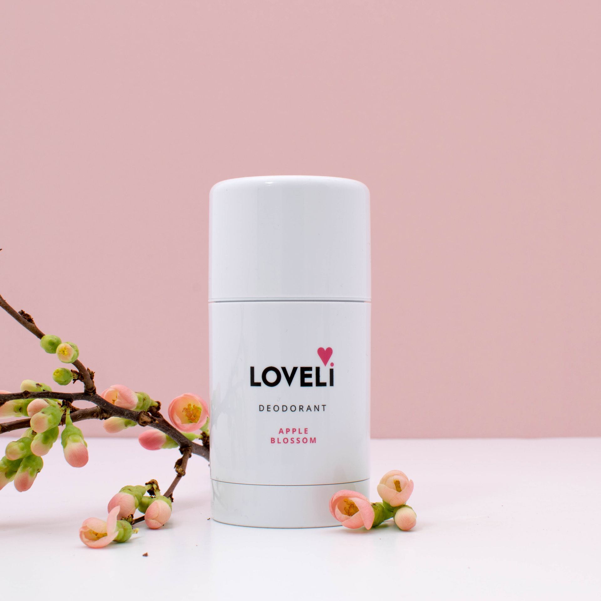 Twee flessen Loveli-deodorant staan op een roze tafel.