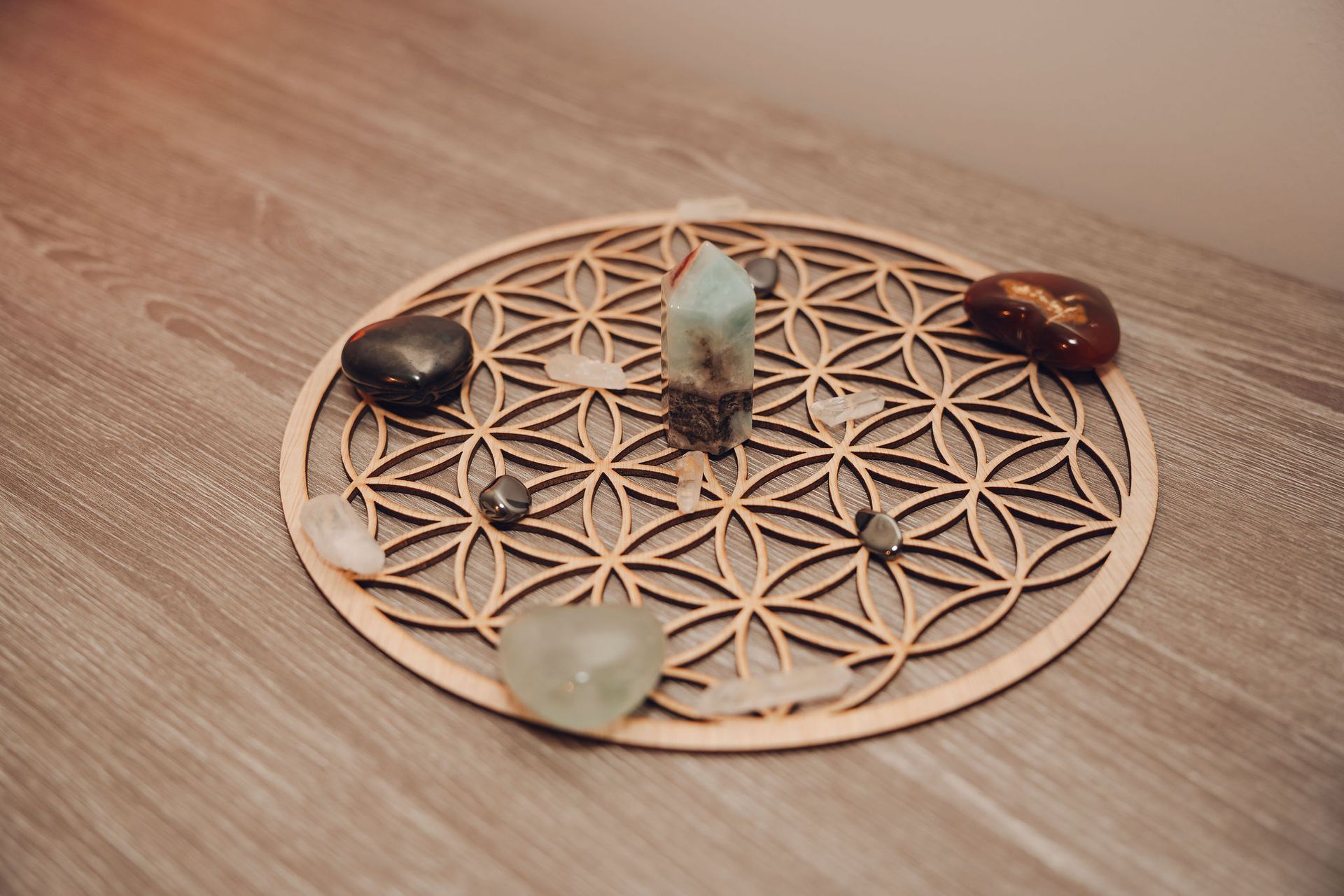 Een houten cirkel met kristallen erop staat op een houten tafel.