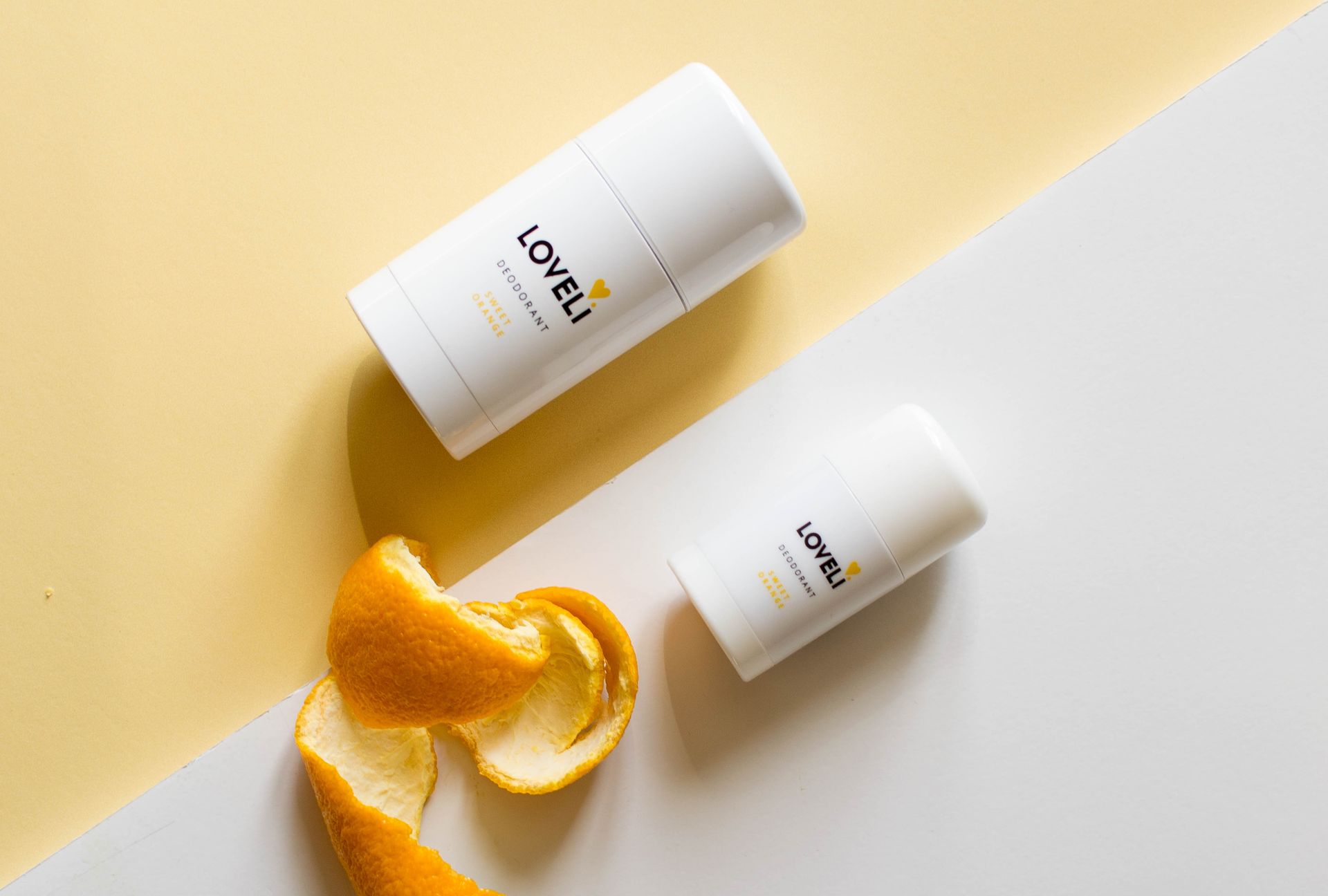 Twee flessen deodorant en een sinaasappelschil op een tafel.