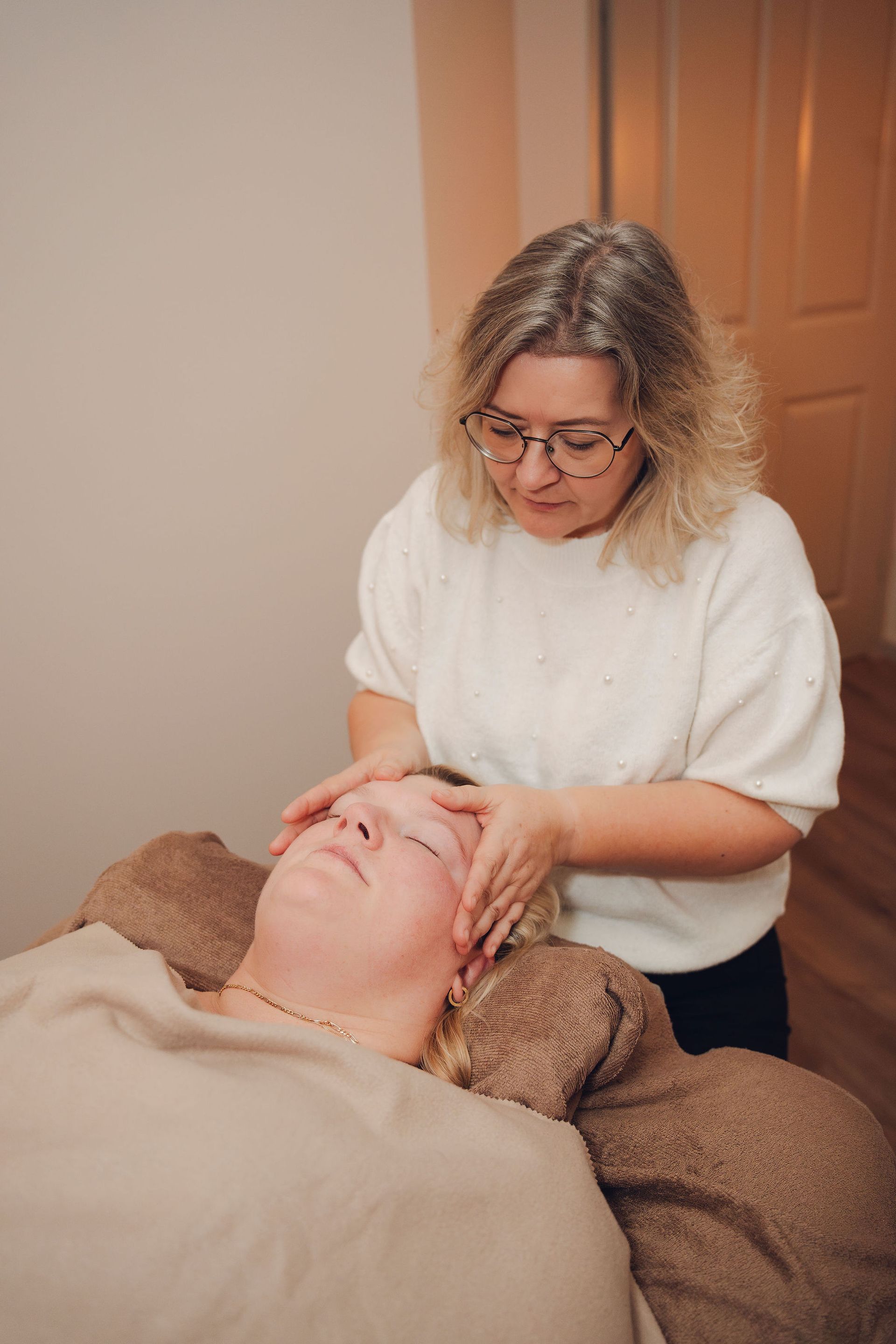 Een vrouw geeft een massage aan een vrouw die op een bed ligt.