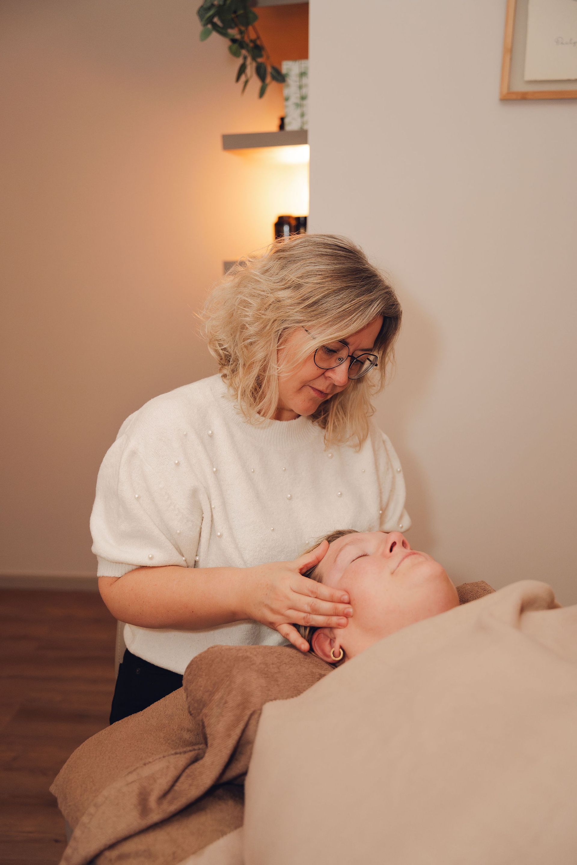 Een vrouw geeft een massage aan een vrouw die op een bed ligt.