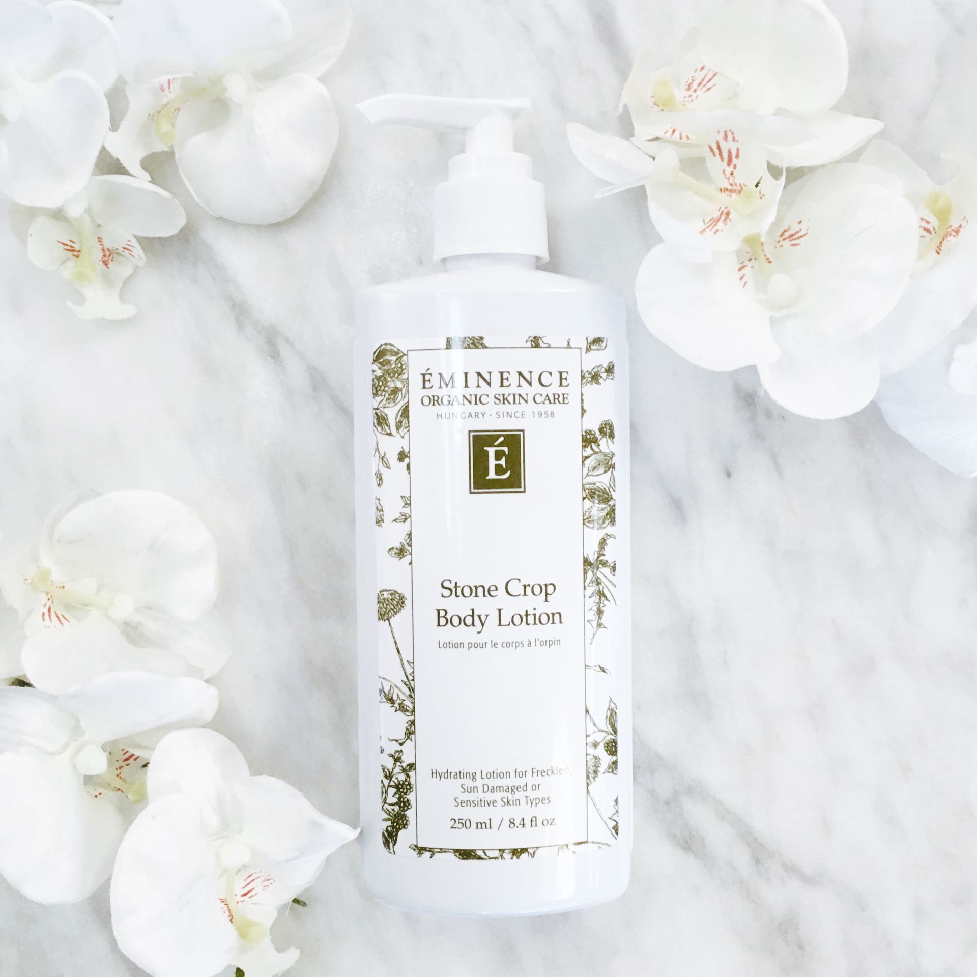 Een witte fles lotion is omgeven door witte bloemen