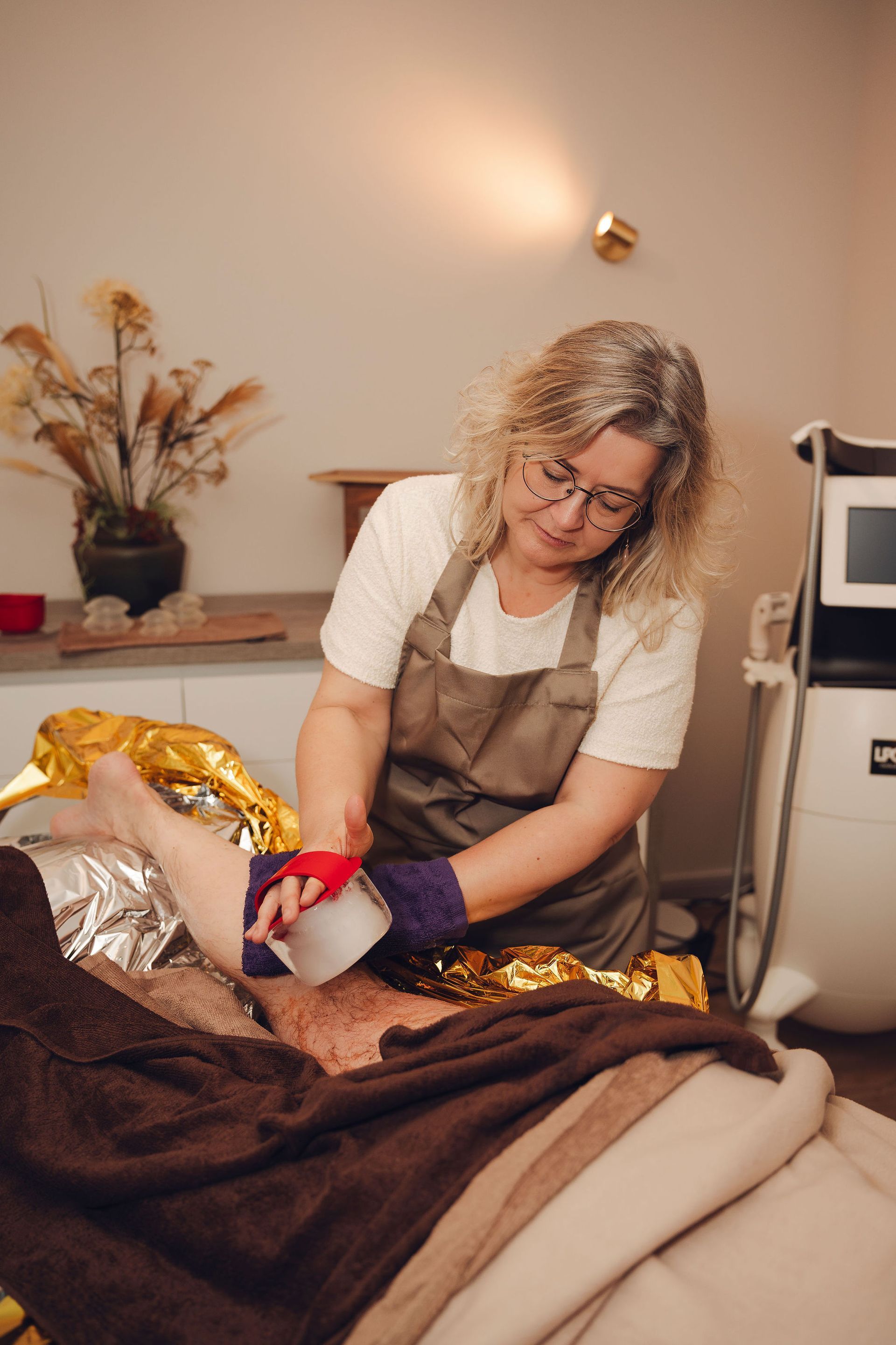 Een vrouw verbindt het been van een man in een schoonheidssalon.