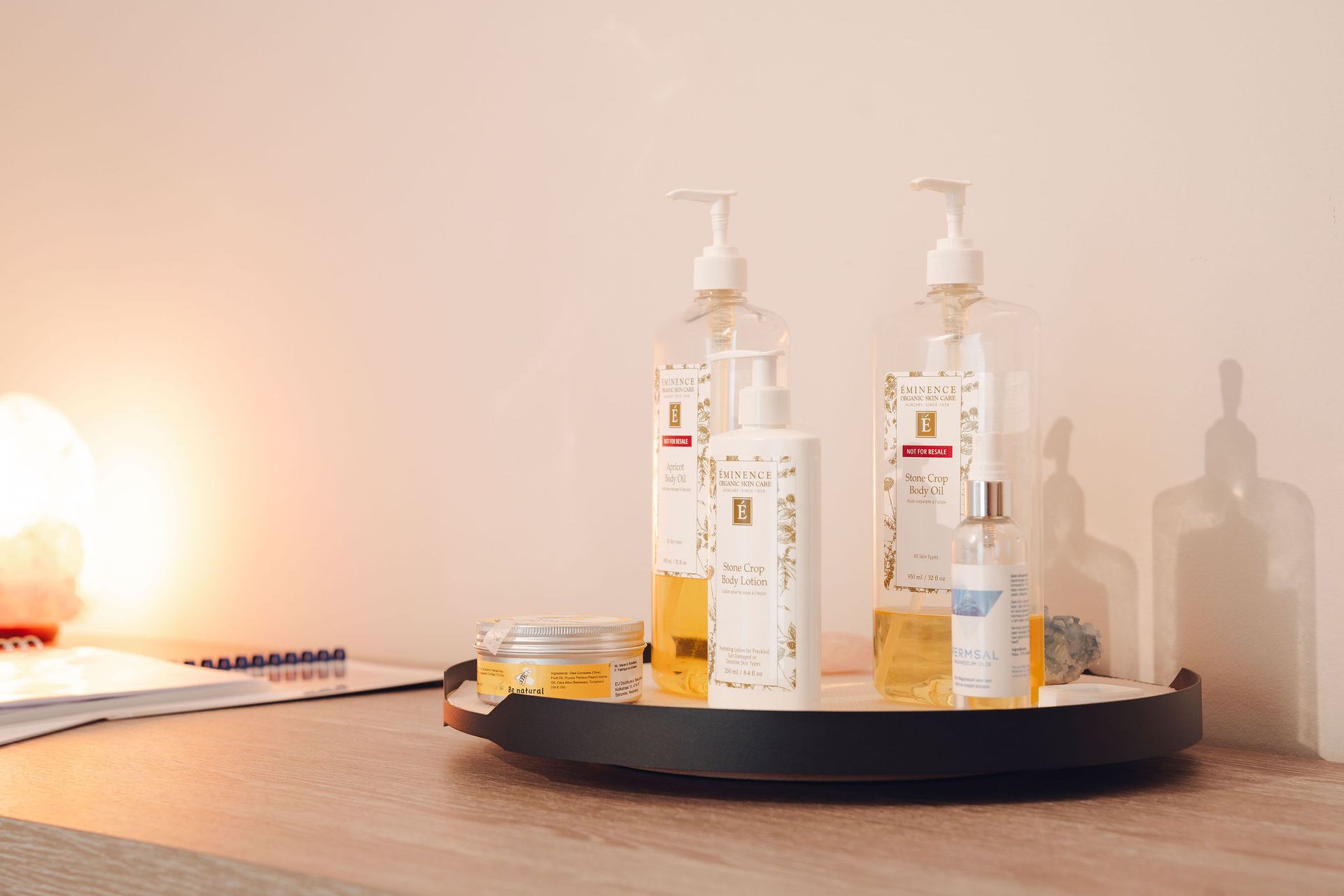 Op een houten tafel staat een dienblad met daarop flesjes cosmetica.